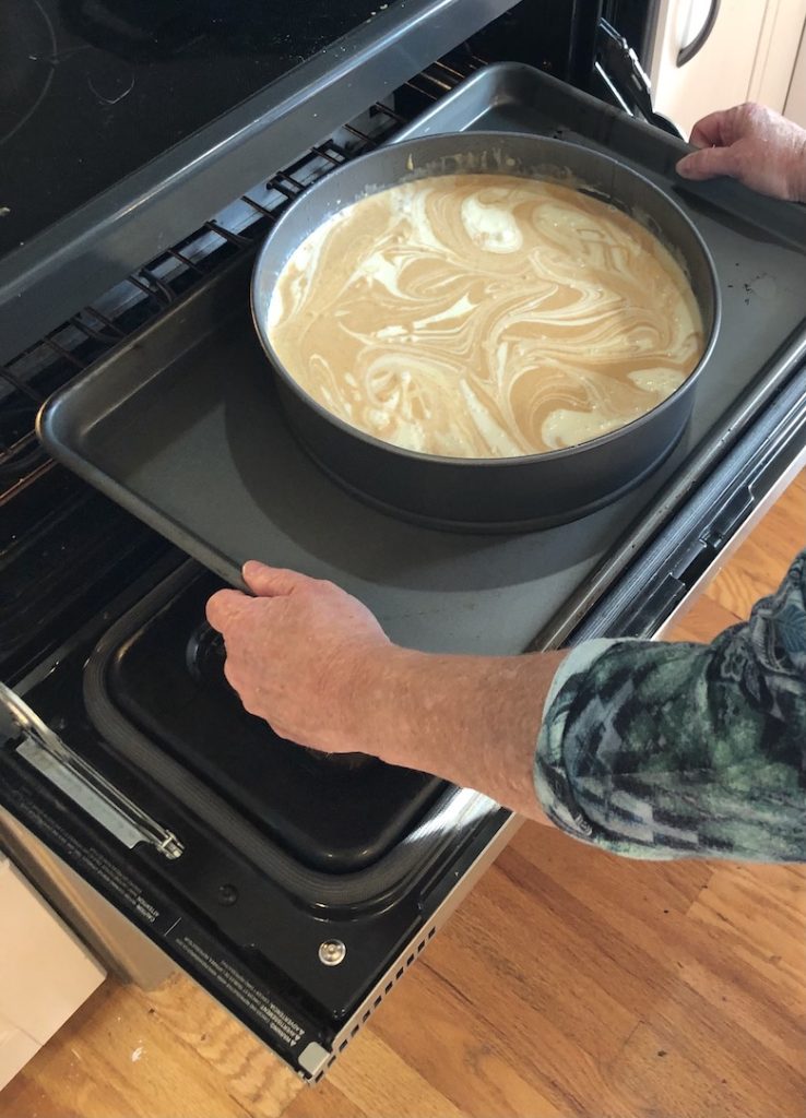 woman put pumpkin cheesecake in the oven