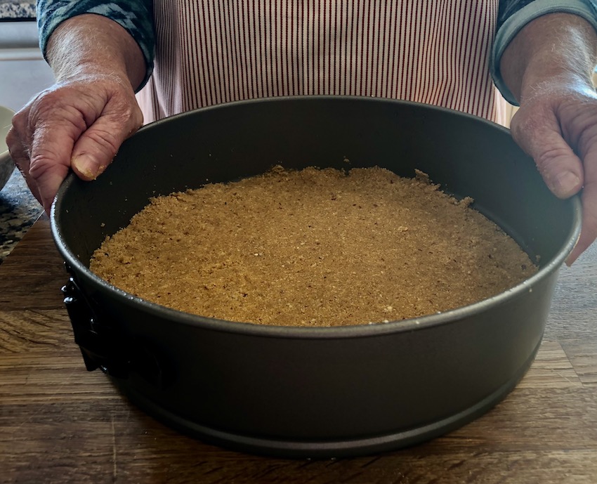 woman holding graham cracker crust before baking