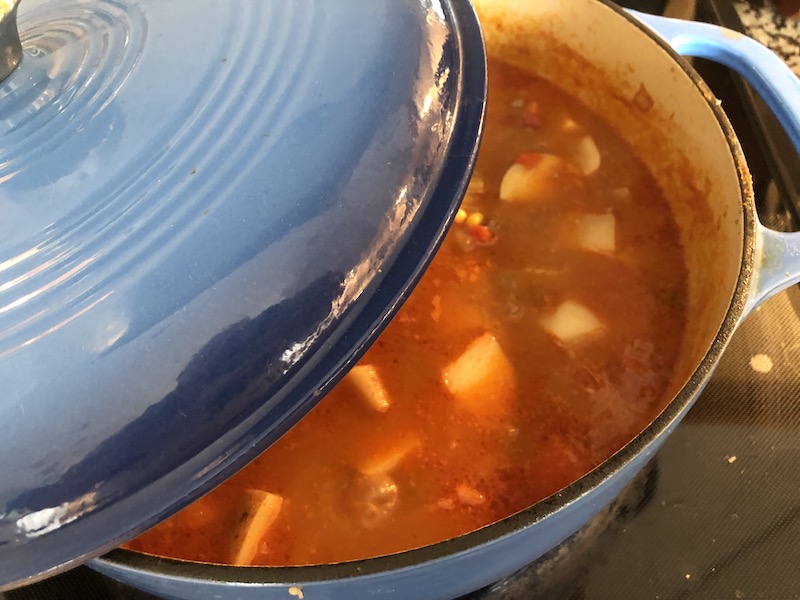 putting a lid on a blue cast iron dutch oven to cook healthy hamburger soup