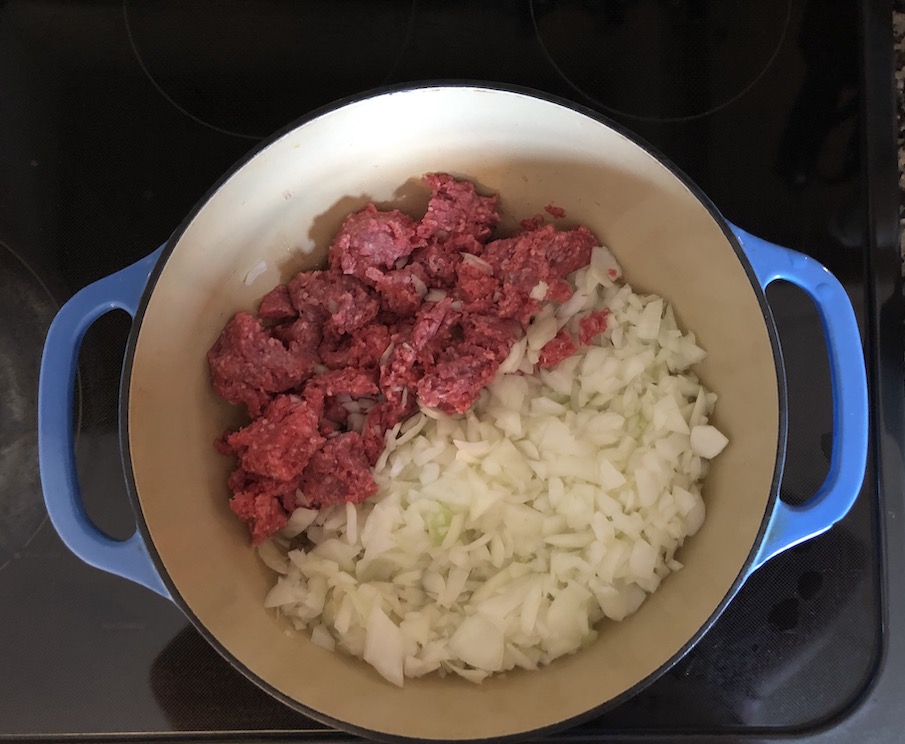 Putting Hamburg and onions in a dutch oven to make hamburger soup
