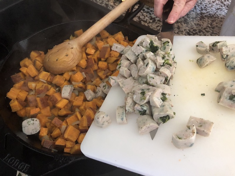 Woman adding sausage to pan