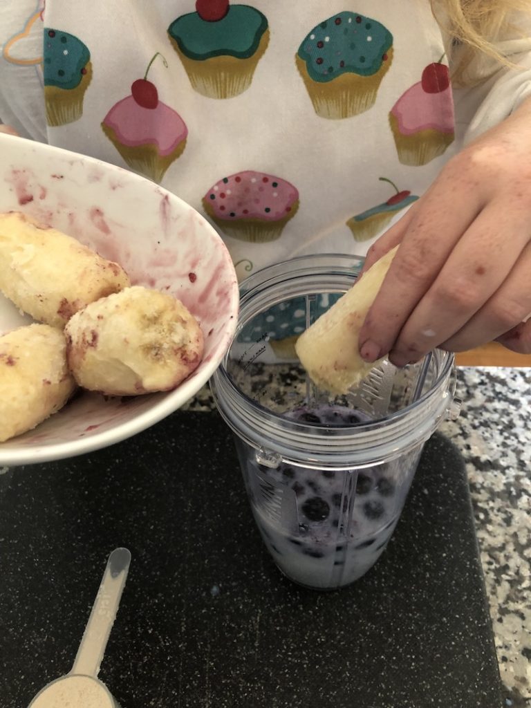 woman adding bananas to blender to make protein shake