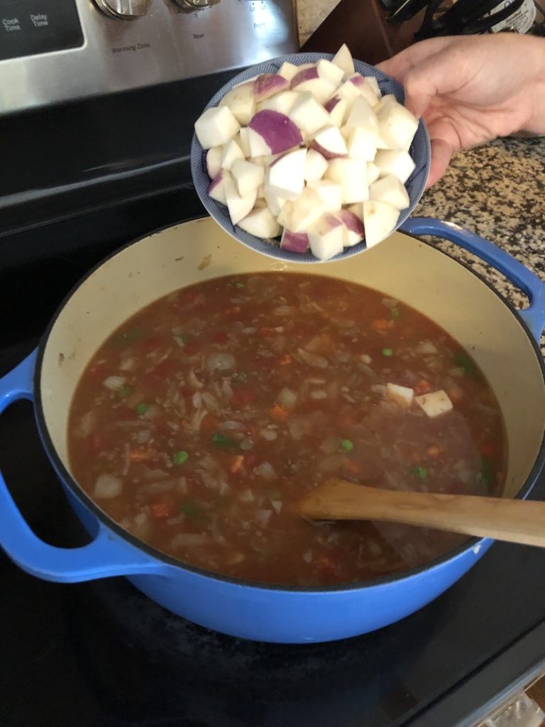 woman adding turnips to soup
