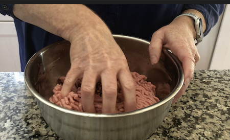 Woman mixing homemade turkey sausage in bowl 
